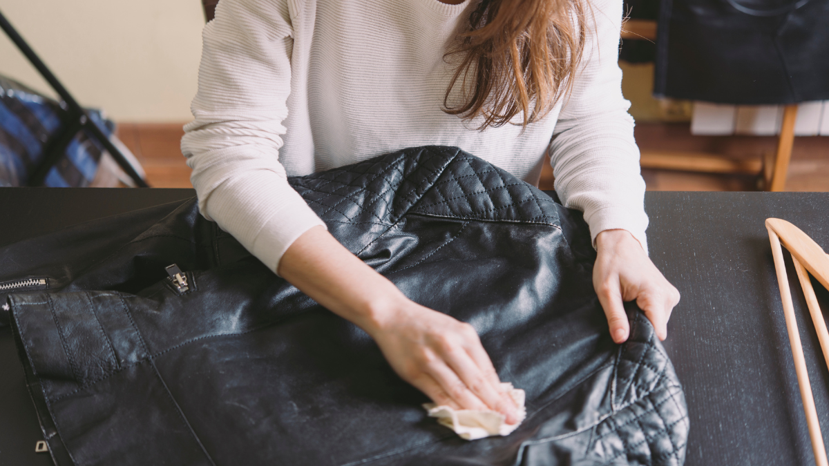 Mujer limpiando una chaqueta de cuero.