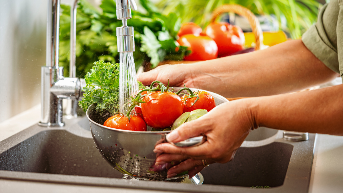 Persona lavando frutas y verduras.