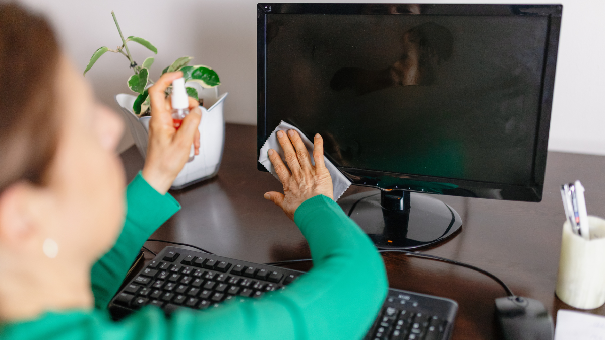 Mujer limpiando la pantalla del computador.