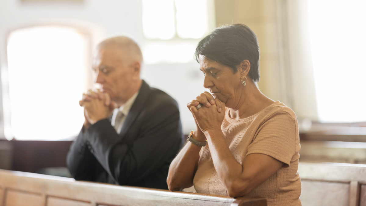 Mujer y hombre en la iglesia orando.