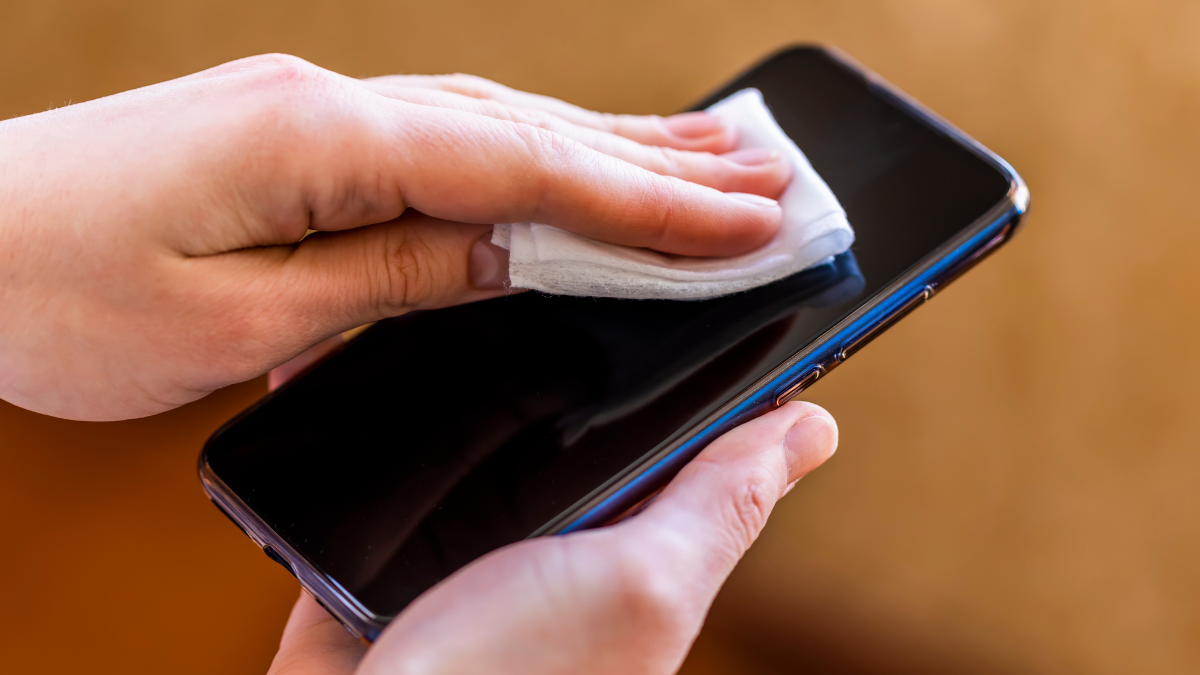 Persona limpiando pantalla de celular con un paño.