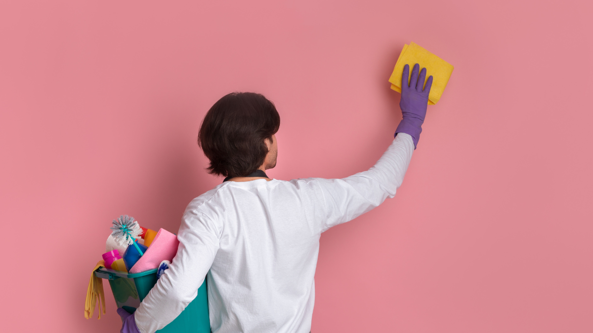 Persona limpiando una pared rosada.